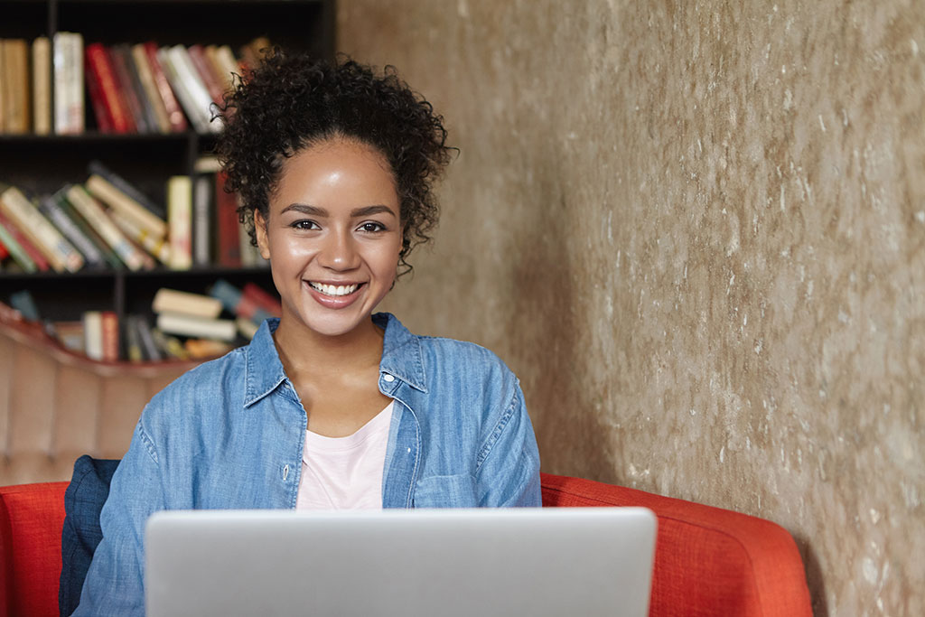 mulher sentada em uma biblioteca com seu laptop